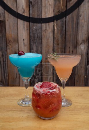 Photo for Cocktails. Closeup view of three alcoholic drinks, blue Margarita frozen, pink grapefruit Margarita and a strawberry daiquiri. - Royalty Free Image