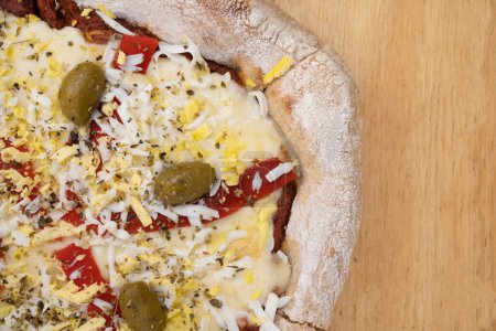 Téléchargez les photos : Vue de dessus d'une pizza au fromage mozzarella, jambon, poivron rouge grillé, œuf et olives vertes sur la table en bois. - en image libre de droit