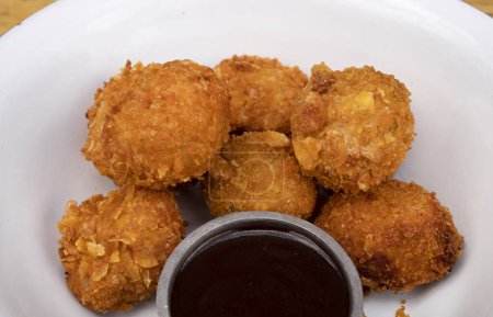 Photo for Closeup view of fried chicken balls with a spicy sauce in a white bowl. - Royalty Free Image
