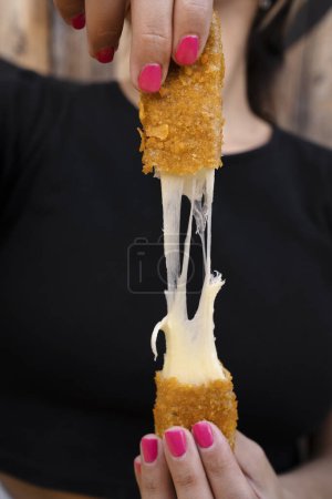 Téléchargez les photos : Femme étirant bâtonnets de fromage mozzarella frits. - en image libre de droit