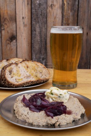 Foto de Vista de cerca del paté con cebolla glaseada y queso azul, panes de centeno y una pinta de cerveza, con un fondo de madera. - Imagen libre de derechos
