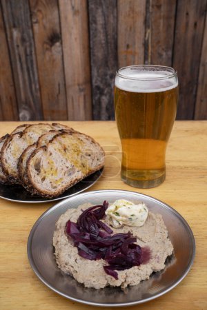 Photo for Menu. Closeup view of pate with glazed onions and blue cheese, rye bread loaves and a pint of beer, with a wooden background. - Royalty Free Image