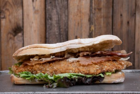 Foto de Sandwich gourmet. Vista de cerca de un sándwich multicapa con filete frito de pollo, tocino, queso y lechuga. - Imagen libre de derechos