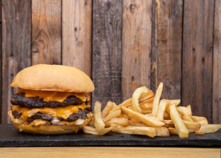 Téléchargez les photos : De la nourriture américaine. Vue rapprochée d'un hamburger monstre à la viande, fromage cheddar et oignon aux frites. - en image libre de droit