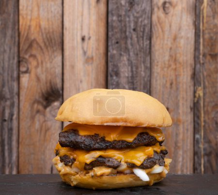 Foto de Comida americana. Vista de cerca de una hamburguesa monstruo con carne, queso cheddar y cebolla. - Imagen libre de derechos