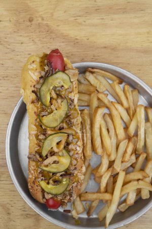 Téléchargez les photos : Hot dog à l'oignon croustillant, concombre tranché et moutarde au miel, frites dans un plat métallique. - en image libre de droit