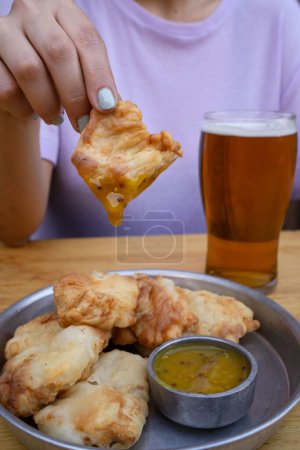 Foto de Enfoque selectivo en una mujer tomando un bocadillo de pollo frito en mostaza. - Imagen libre de derechos