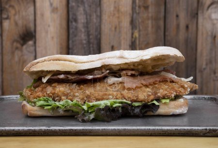 Photo for Gourmet sandwich. Closeup view of a multilayer sandwich with chicken fried steak, bacon, cheese and lettuce. - Royalty Free Image