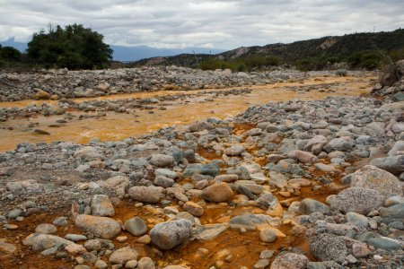 Foto de Río Amarillo llamado Río de Oro debido a la presencia de hierro en el agua, fluyendo a través del valle rocoso, bosque y montañas en La Rioja, Argentina. - Imagen libre de derechos