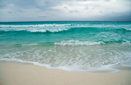 Foto de Vacaciones. Paisaje marino. Mar de agua de color turquesa. La arena blanca y las olas del océano bajo un cielo tormentoso dramático en Cancún, México. - Imagen libre de derechos