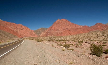 Téléchargez les photos : Voyage dans la nature. Voyager le long de la courbe de route asphaltée à travers le désert aride et la vallée. L'autoroute vide, sable, grès et collines rocheuses sous un ciel bleu profond. - en image libre de droit