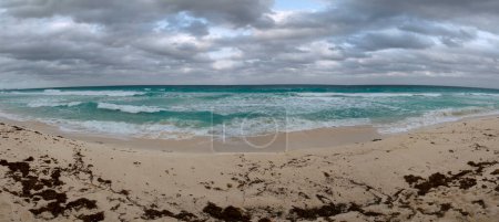 Foto de Vacaciones. Vista panorámica de la playa bajo un cielo dramático. The white sand, shore, coast line, turquoise color water ocean and sea waves in Cancún, México. - Imagen libre de derechos