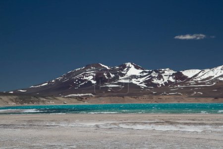 Foto de El paisaje alpino. Vista panorámica del lago de agua glaciar turquesa llamado Lago Verde, muy alto en las montañas de los Andes. Las salinas, el agua y las montañas con picos nevados bajo un cielo azul profundo. - Imagen libre de derechos