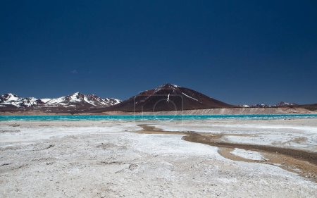 Téléchargez les photos : Paysage volcanique dans la chaîne de montagnes des Andes. Vue panoramique sur le lac d'eau turquoise appelé Green Lagoon, les montagnes sombres avec des sommets enneigés et des volcans, haut dans la cordillère. - en image libre de droit