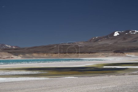 Téléchargez les photos : Paysage volcanique. Vue de l'étang jaune et noir en raison du soufre dans l'eau, du lac d'eau du glacier turquoise, du sel naturel plat et des montagnes des Andes en arrière-plan, sous un ciel bleu profond. - en image libre de droit