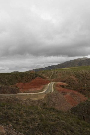 Foto de Camino de asfalto vacío a través de los acantilados rocosos rojos y las montañas. Viajando por la carretera Miranda Slope en La Rioja, Argentina. - Imagen libre de derechos