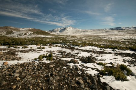 Foto de El paisaje alpino. Vista panorámica del campo de nieve bajo un cielo azul claro en un día soleado, con montañas en el fondo. - Imagen libre de derechos