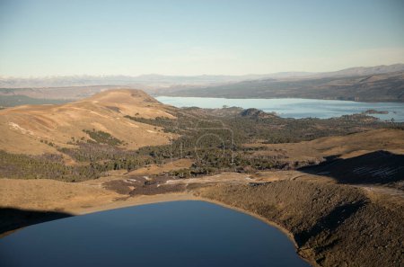 Téléchargez les photos : Vue sur le lac de cratère d'eau bleu profond, la forêt, la prairie jaune et les montagnes des Andes, du sommet du volcan Batea Mahuida. - en image libre de droit