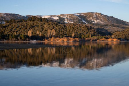 Photo for Symmetry in nature. Enchanting view of the Andes mountain range, forest and sky, and the reflection in lake Alumin water surface at sunset, in Villa Pehuenia, Neuqun, Patagonia Argentina. - Royalty Free Image