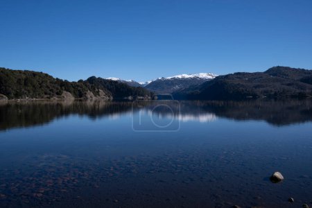 Photo for Alpine landscape in summer. Panorama view of the calm lake, forest and volcano Batea Mahuida, under a deep blue sky. Beautiful environment reflection in the water surface. - Royalty Free Image