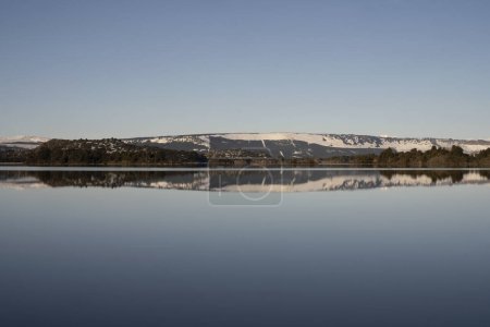 Téléchargez les photos : Vue du lac calme et du ciel bleu, reflet de la forêt et des montagnes à la surface de l'eau. - en image libre de droit