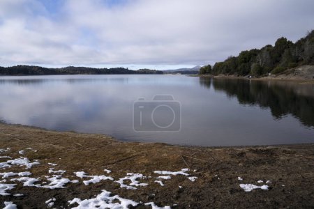 Téléchargez les photos : Le lac calme. Vue du rivage, de la baie, de la forêt et du ciel nuageux reflet à la surface de l'eau, par une journée d'hiver. - en image libre de droit