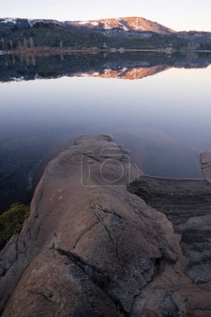 Photo for The lake at sunset. View of the rocky shore, lake Alumine, forest, mountains and their reflection in the water, at nightfall in Villa Pehuenia, Patagonia Argentina. - Royalty Free Image