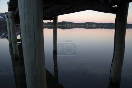 Photo for Magical view of the lake at sunset, seen from under the wooden dock. - Royalty Free Image