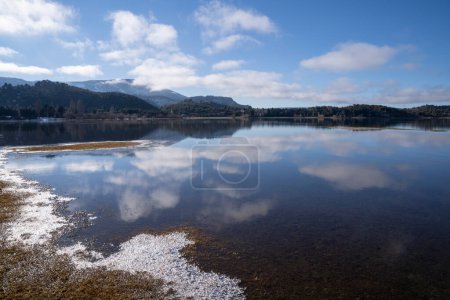 Téléchargez les photos : Le lac calme dans une matinée ensoleillée. Vue panoramique sur la forêt, le lac et le reflet parfait du ciel dans l'eau bleue. La chaîne de montagnes des Andes en arrière-plan. - en image libre de droit
