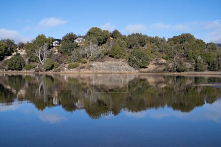 Téléchargez les photos : Vue panoramique sur les maisons en bois du lac dans la forêt. Le rivage, le bois, les falaises et le reflet du ciel bleu dans l'eau. - en image libre de droit