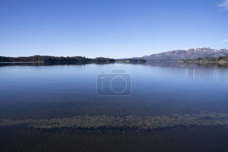 Téléchargez les photos : Le lac par une matinée ensoleillée. Vue panoramique sur la forêt, le lac et le reflet parfait du ciel dans l'eau bleue. La chaîne de montagnes des Andes en arrière-plan. - en image libre de droit