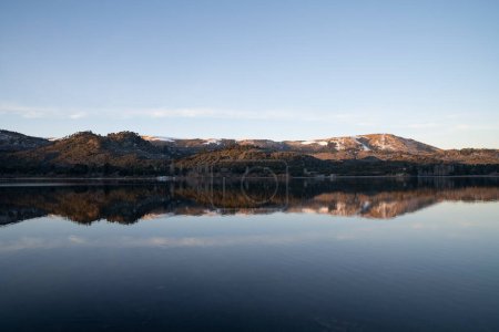 Photo for The placid lake at sunset. The clear blue sky, forest and mountains in the horizon, reflected in the water surface. - Royalty Free Image