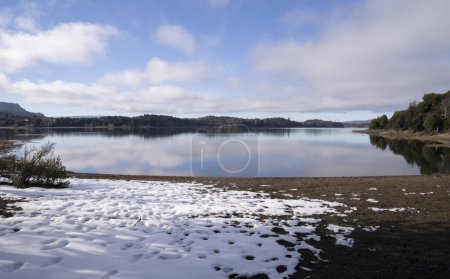 Téléchargez les photos : Paysage hivernal magique en Patagonie. Vue de la neige sur le rivage, le lac, les montagnes, la forêt et le ciel bleu avec des nuages blancs reflet parfait à la surface de l'eau. - en image libre de droit