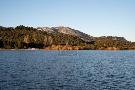 Photo for The blue water lake at sunset. The shoreline, forest and mountains in the background. - Royalty Free Image