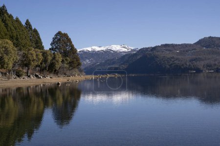 Téléchargez les photos : Vue sur le volcan Batea Mahuida, les montagnes des Andes, la forêt et le lac d'Alumine à Villa Pehuenia, Patagonie Argentine. Beau paysage et reflet du ciel bleu dans l'eau du glacier. - en image libre de droit