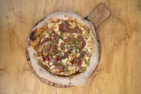 Photo for Top view of a pizza made with tomato sauce, mozzarella cheese, crispy bacon and onions, with a wooden background. - Royalty Free Image