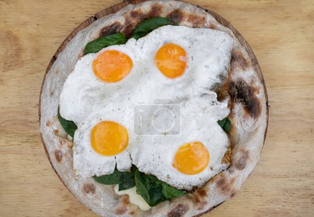 Téléchargez les photos : Vue de dessus d'une pizza au fromage mozzarella, aux épinards et aux œufs frits, sur la table en bois. - en image libre de droit