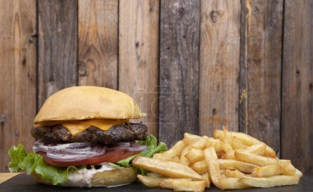 Téléchargez les photos : Burger de bœuf savoureux avec frites sur table en bois. - en image libre de droit