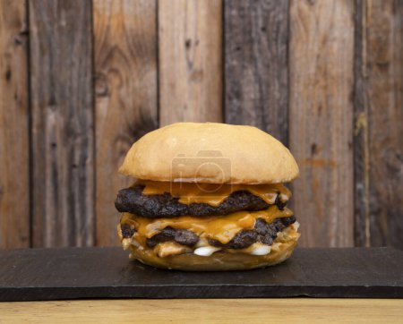 Foto de Comida americana. Vista de cerca de una hamburguesa monstruo con carne, queso cheddar y cebolla. - Imagen libre de derechos