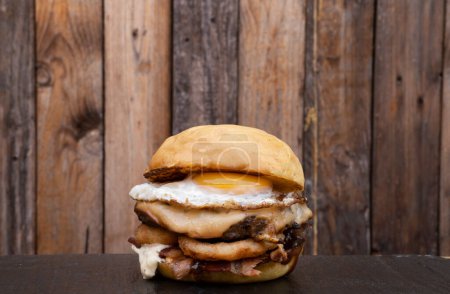 Téléchargez les photos : Burger multicouche avec viande grillée, fromage provolone, rondelles d'oignon bacon, sauce barbecue et un œuf grillé. - en image libre de droit