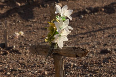 Foto de Cultura y religión. Vista de cerca de una cruz sagrada tradicional decorada con flores de papel en el antiguo cementerio aborigen en las áridas montañas. - Imagen libre de derechos