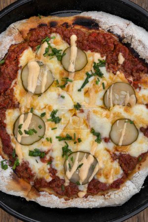 Téléchargez les photos : Fond de pizza coloré. Vue rapprochée d'une pizza à la viande hachée, sauce tomate, concombre grillé, aïoli à l'ail et ciboulette, dans la poêle à pizza. - en image libre de droit