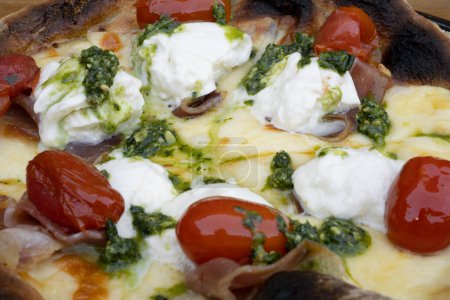 Téléchargez les photos : Vue rapprochée d'une pizza avec mozzarella et fromage burrata, tomates cerises et prosciutto. - en image libre de droit