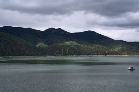 Foto de Plácida vista del sereno lago y verdes colinas. Un barco en el agua. - Imagen libre de derechos