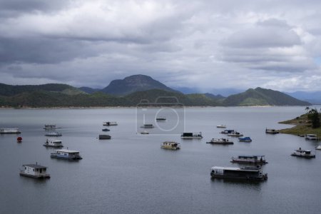 Foto de Vista de las casas flotantes, lago y colinas bajo un cielo nublado. - Imagen libre de derechos