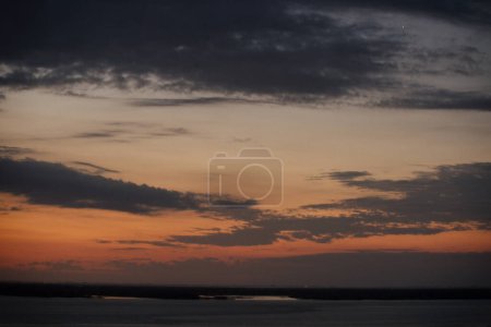 Foto de Dramática vista del río y la costa al anochecer. Hermosa puesta de sol reflejo del cielo en la superficie del agua. - Imagen libre de derechos