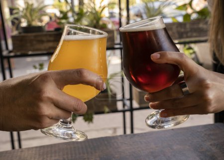 Téléchargez les photos : Deux femmes grillent avec une bière ambre et une bière blonde en plein air. - en image libre de droit
