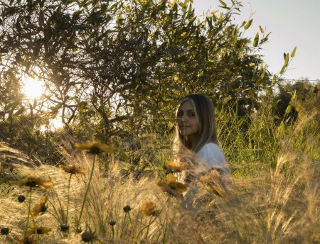 Photo for Beautiful girl in the field. Portrait of young attractive woman laying in the field at sunset. Coreopsis grandiflora yellow flowers and Stipa ornamental grasses in the park. - Royalty Free Image