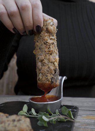 Photo for Finger food. Closeup view of a woman dipping a fried mozzarella stick in bbq sauce. - Royalty Free Image
