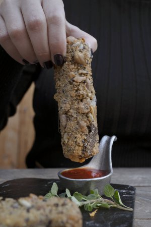 Photo for Finger food. Closeup view of a woman dipping a fried mozzarella stick in bbq sauce. - Royalty Free Image